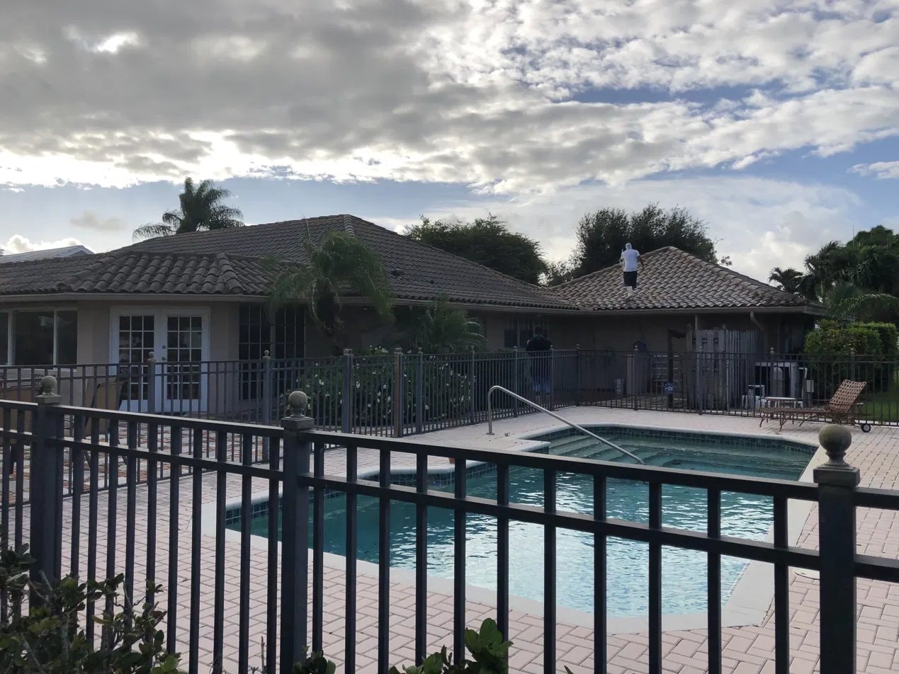 Soft-wash roof cleaning - flat tile roof above screened pool, Atlantis, FL