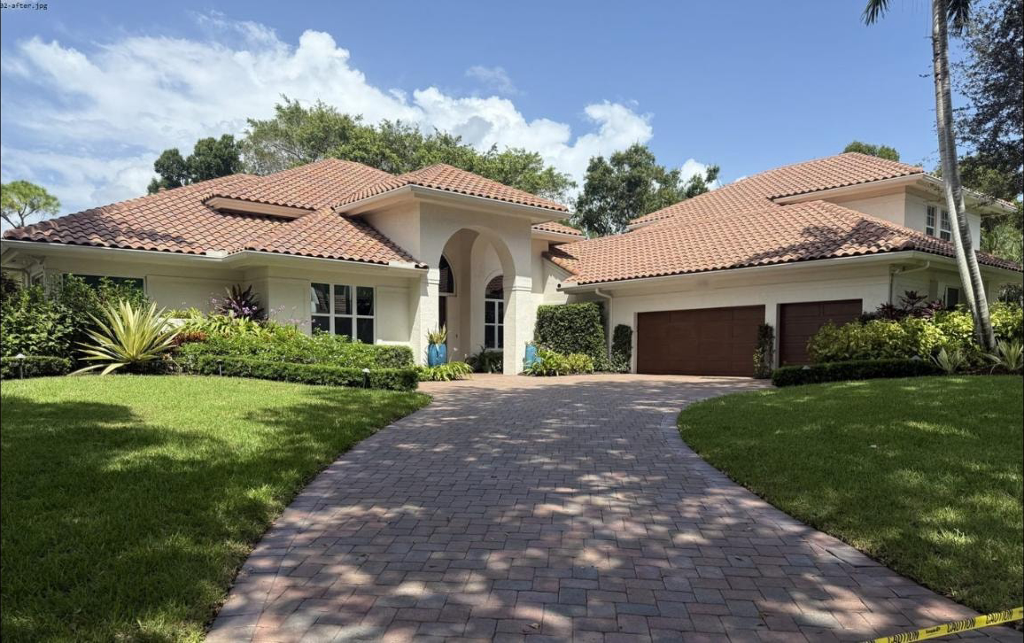 After: Same Boca Raton home after soft-wash roof cleaning and paver driveway pressure washing — caution tape across freshly cleaned driveway