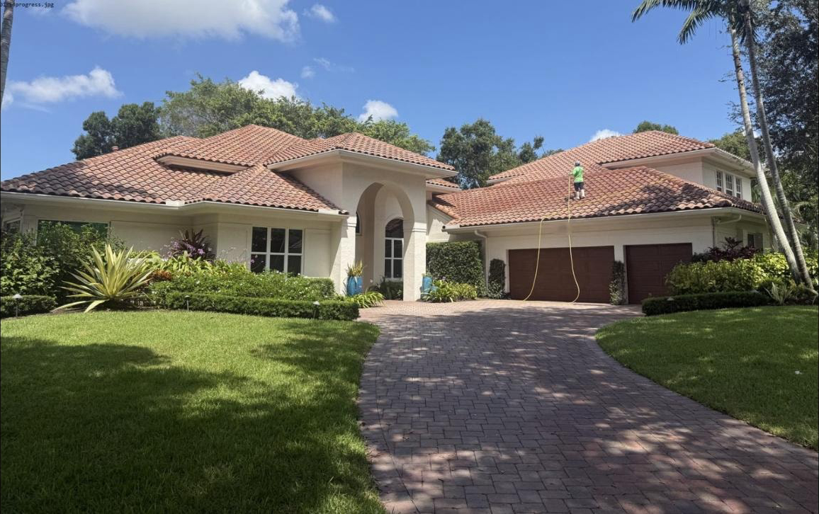 Before: Technician on the roof applying soft-wash solution — Boca Raton, FL, day one of two-day job