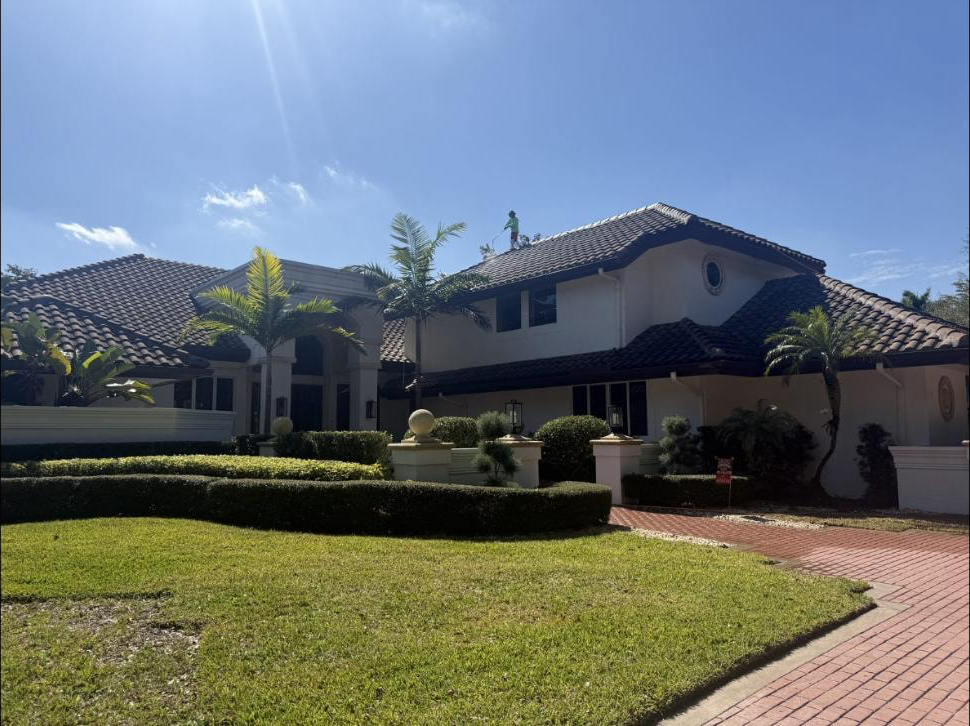 Before: Technician on the roof of a Boca Raton estate during soft-wash barrel tile roof cleaning, February