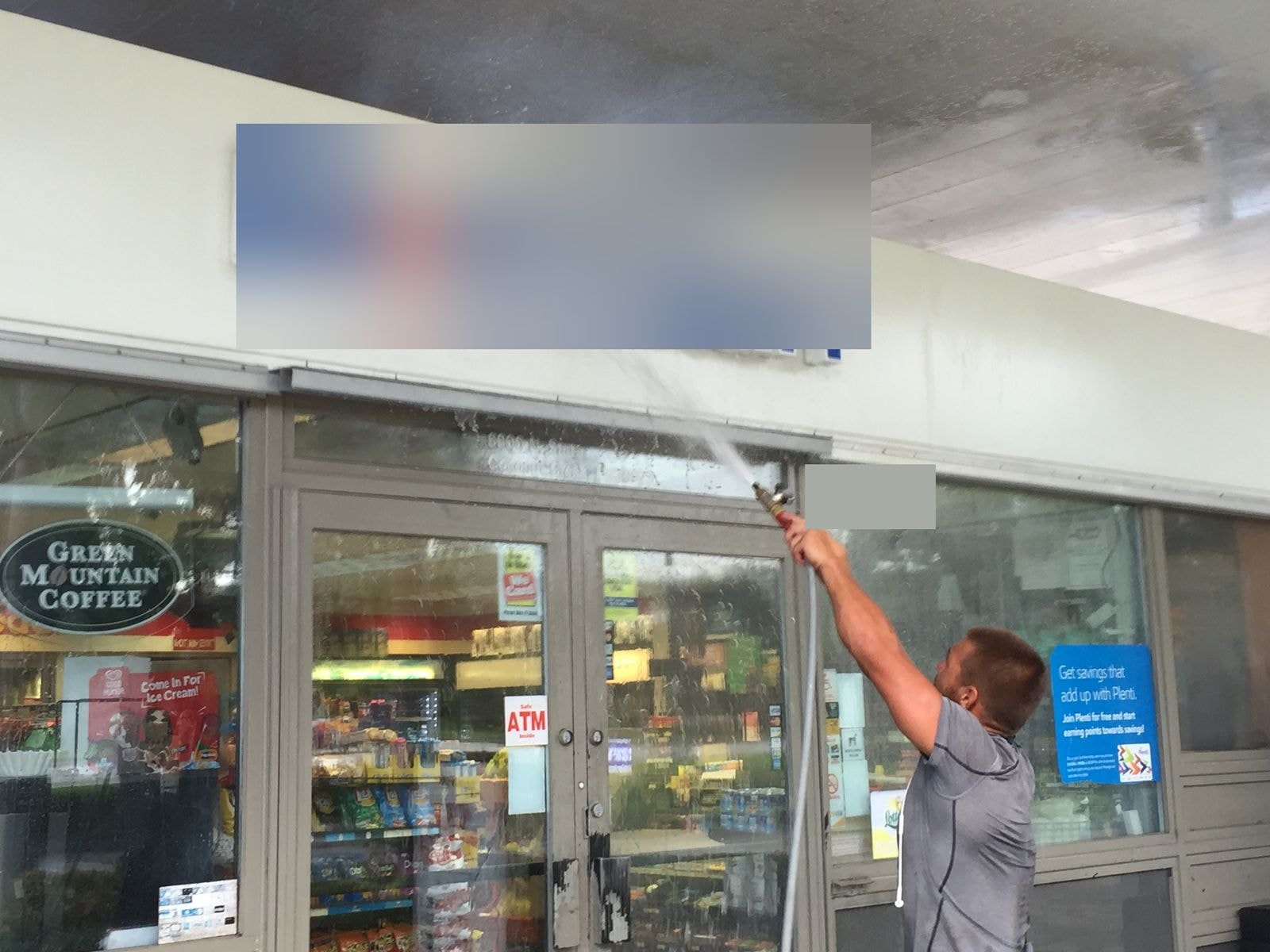 Technician pressure washing a commercial storefront sign and fascia in Coconut Creek, Florida