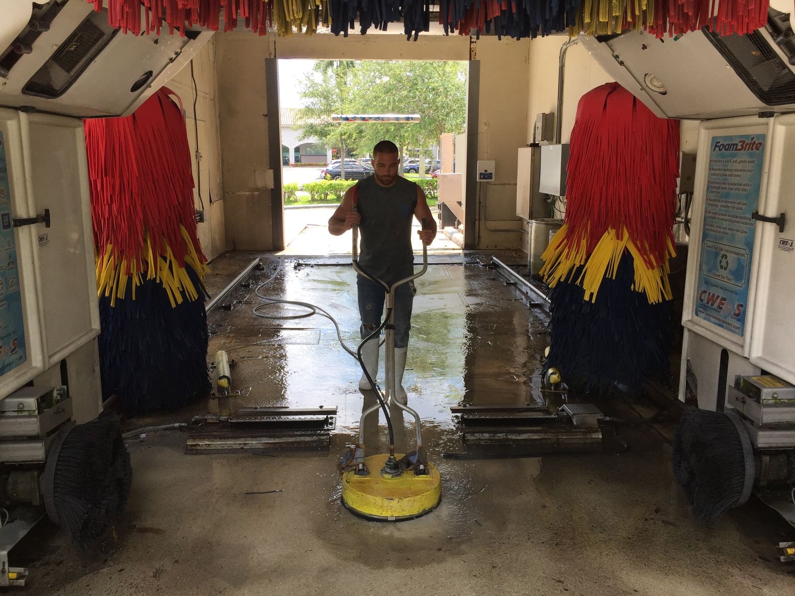 Technician operating a surface cleaner on a car wash tunnel floor in Coconut Creek, Florida