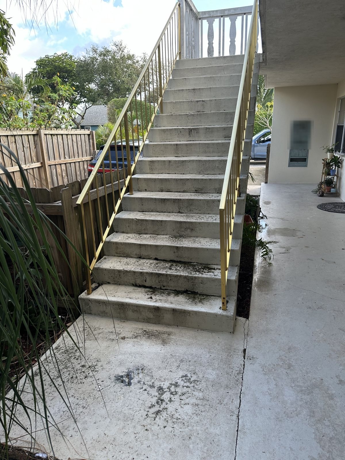 Before: Before and after pressure washing of concrete stairs with gold metal railings — heavy algae staining fully removed, Lake Worth, FL