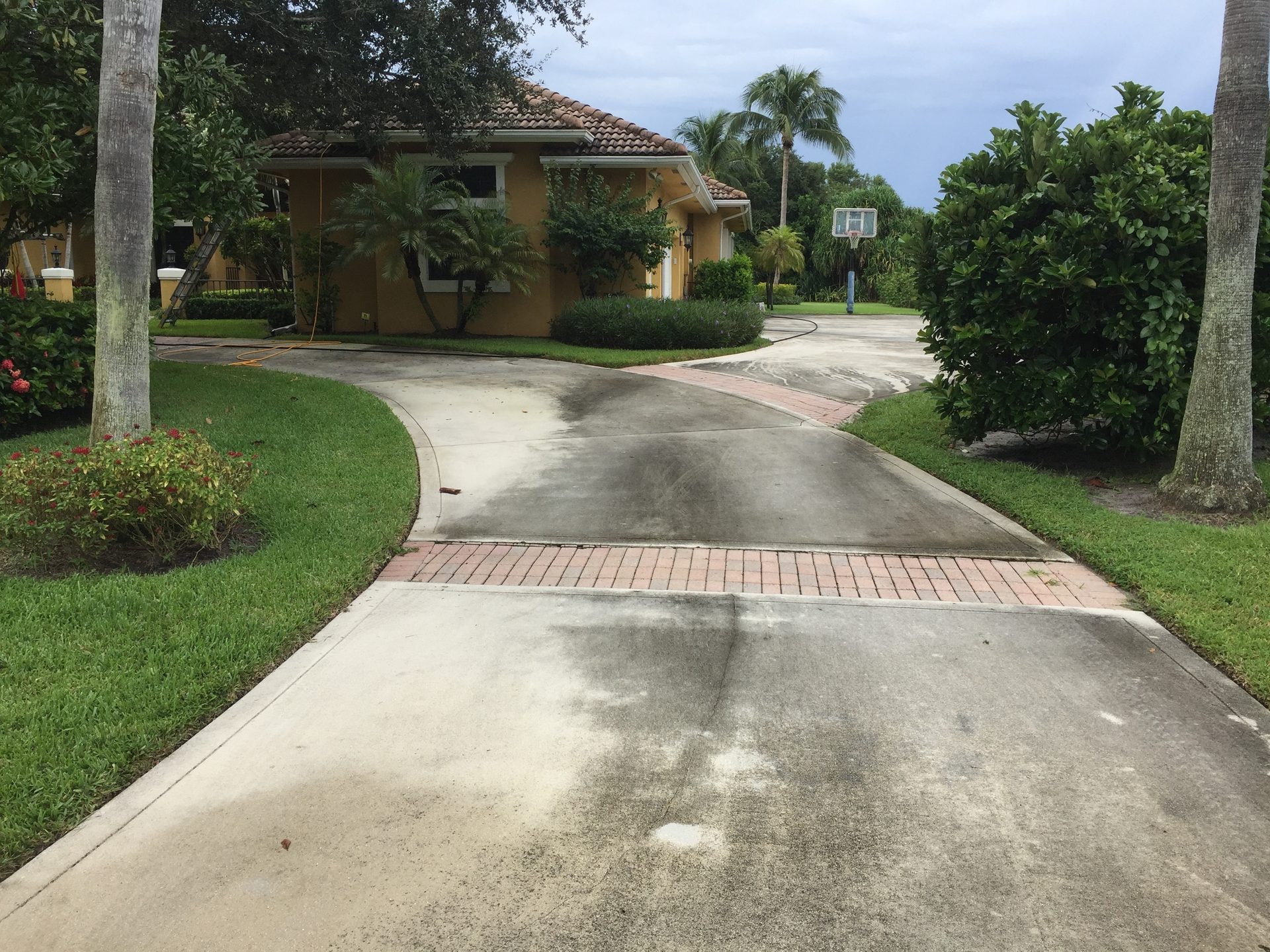 Before: Concrete driveway with heavy staining and organic growth before pressure washing, Palm Beach Gardens, FL