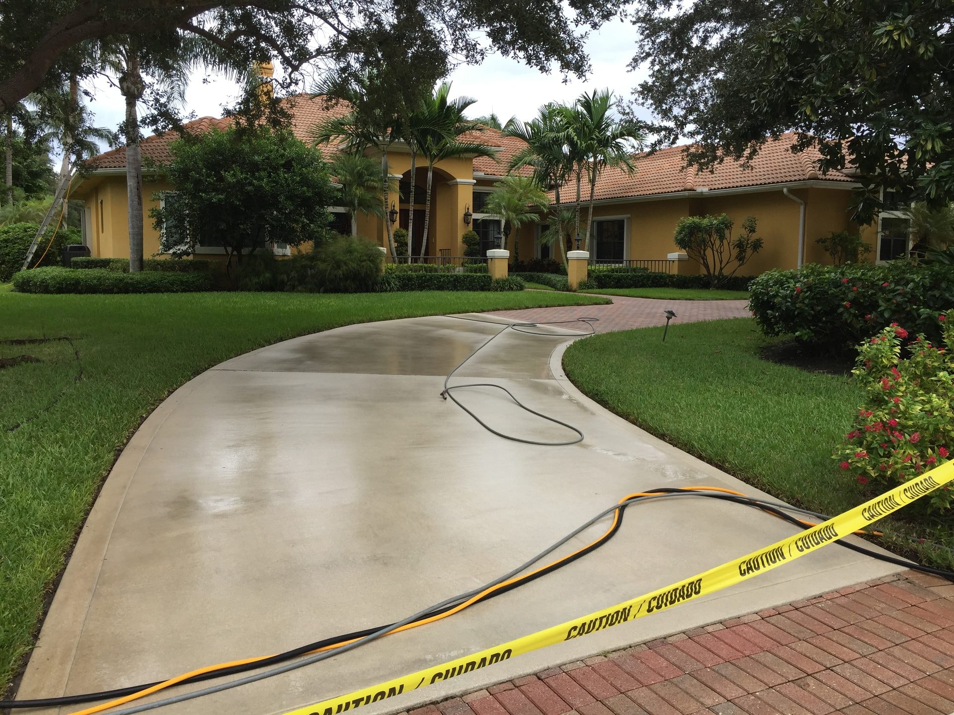 Concrete driveway during pressure washing with hoses on the wet surface, Palm Beach Gardens, FL