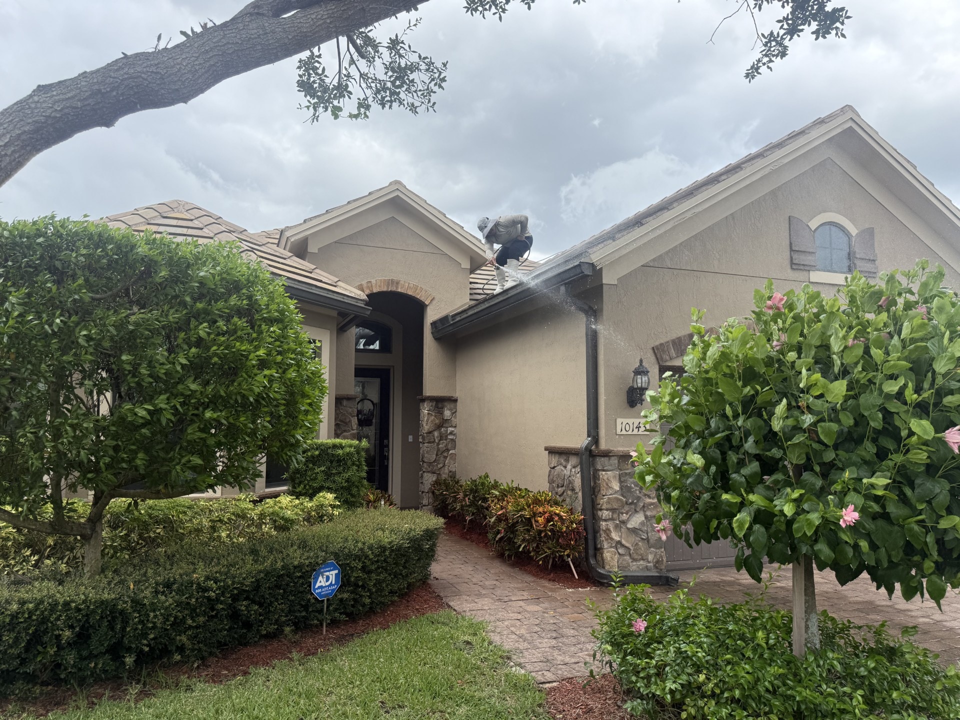 Technician flushing debris from clogged gutters at a Wellington home, Wellington, FL