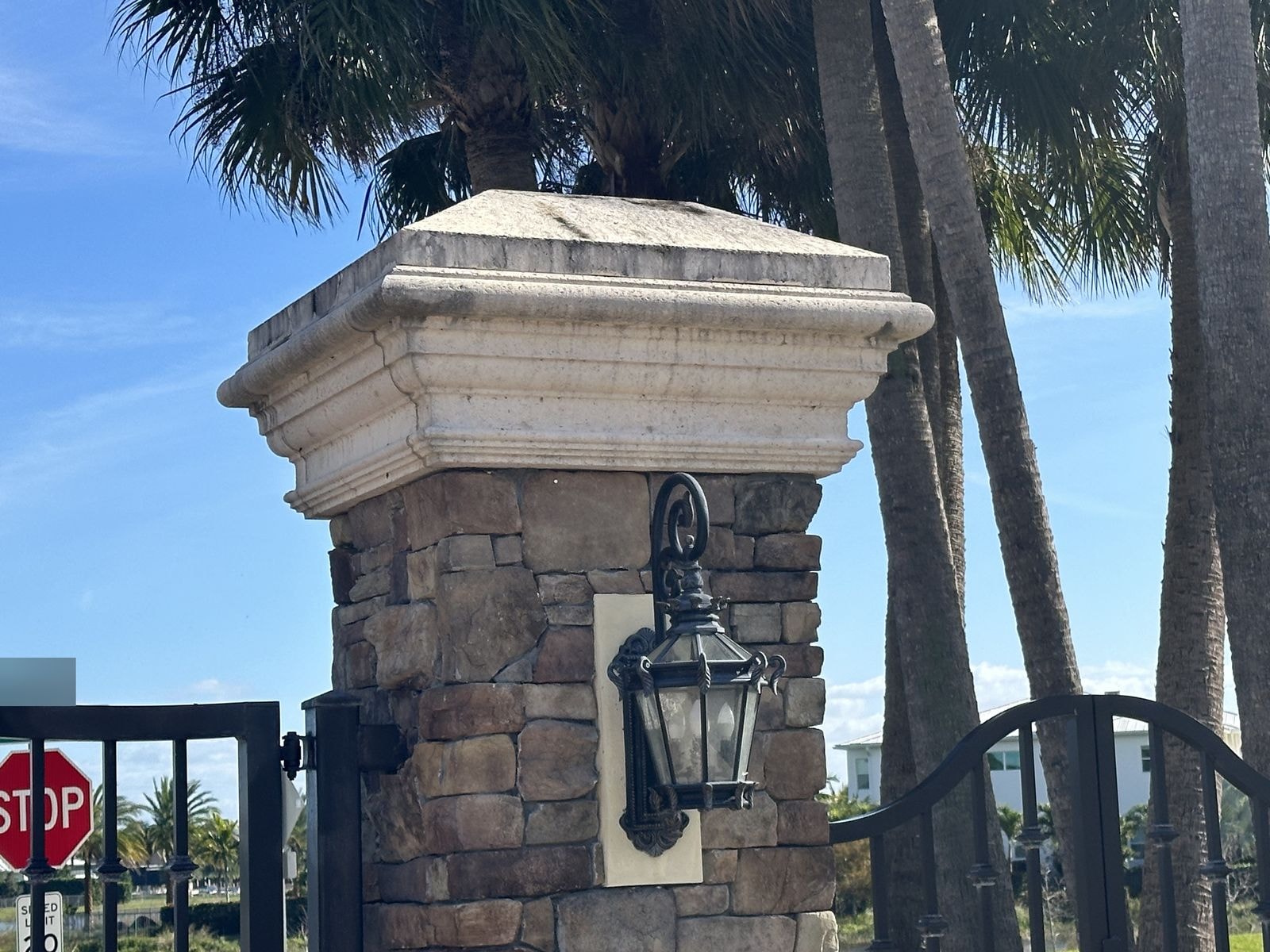 Before: Stone entry column with lantern before cleaning, staining visible on cap, gated HOA community, Jupiter, FL