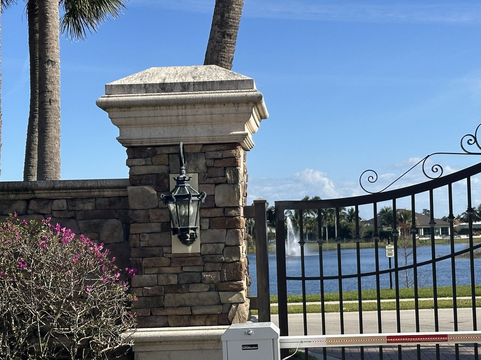 Before: Lakefront stone entry column with lantern before cleaning, staining visible on cap, Jupiter, FL