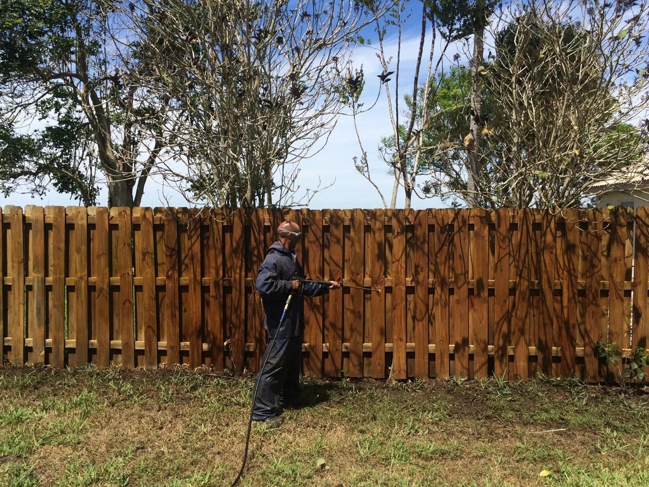 Technician pressure washing a wood shadowbox fence to restore the wood in Jupiter, FL