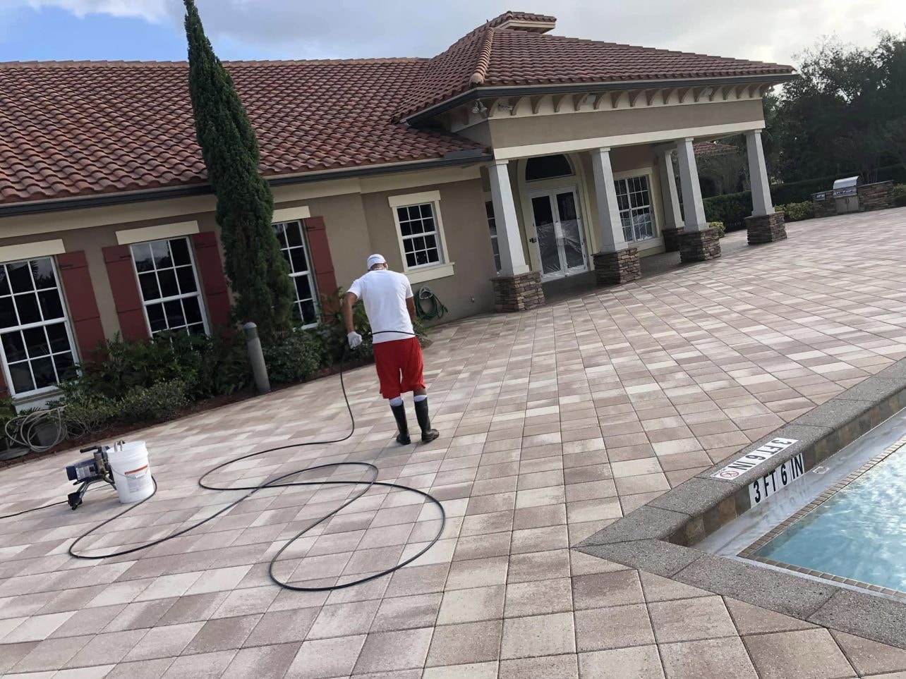 Before: Technician applying sealer to the paver deck at an HOA community pool, Wellington, FL