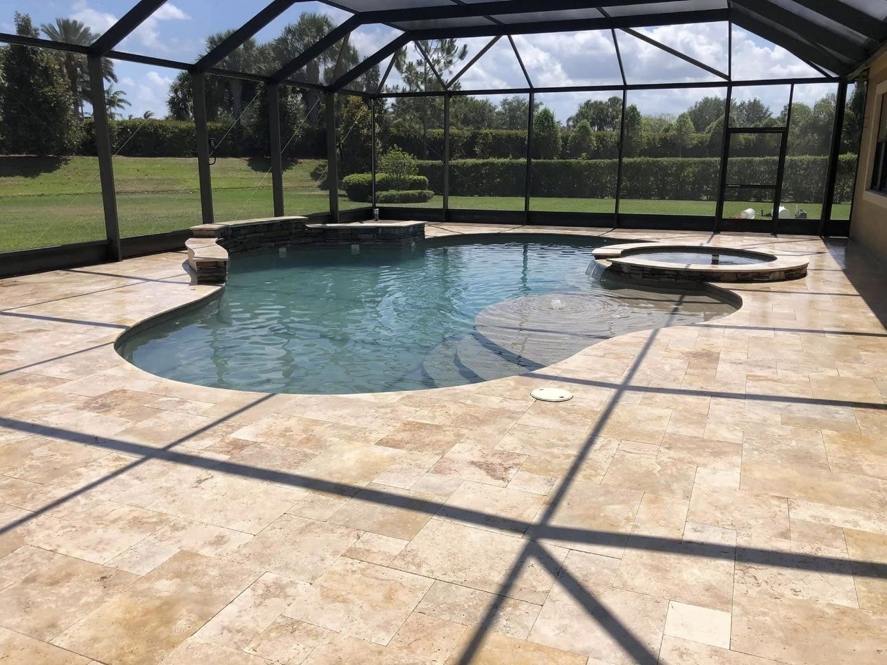 After: Screen enclosed travertine pool deck after cleaning with clean joints and restored stone, Wellington, FL