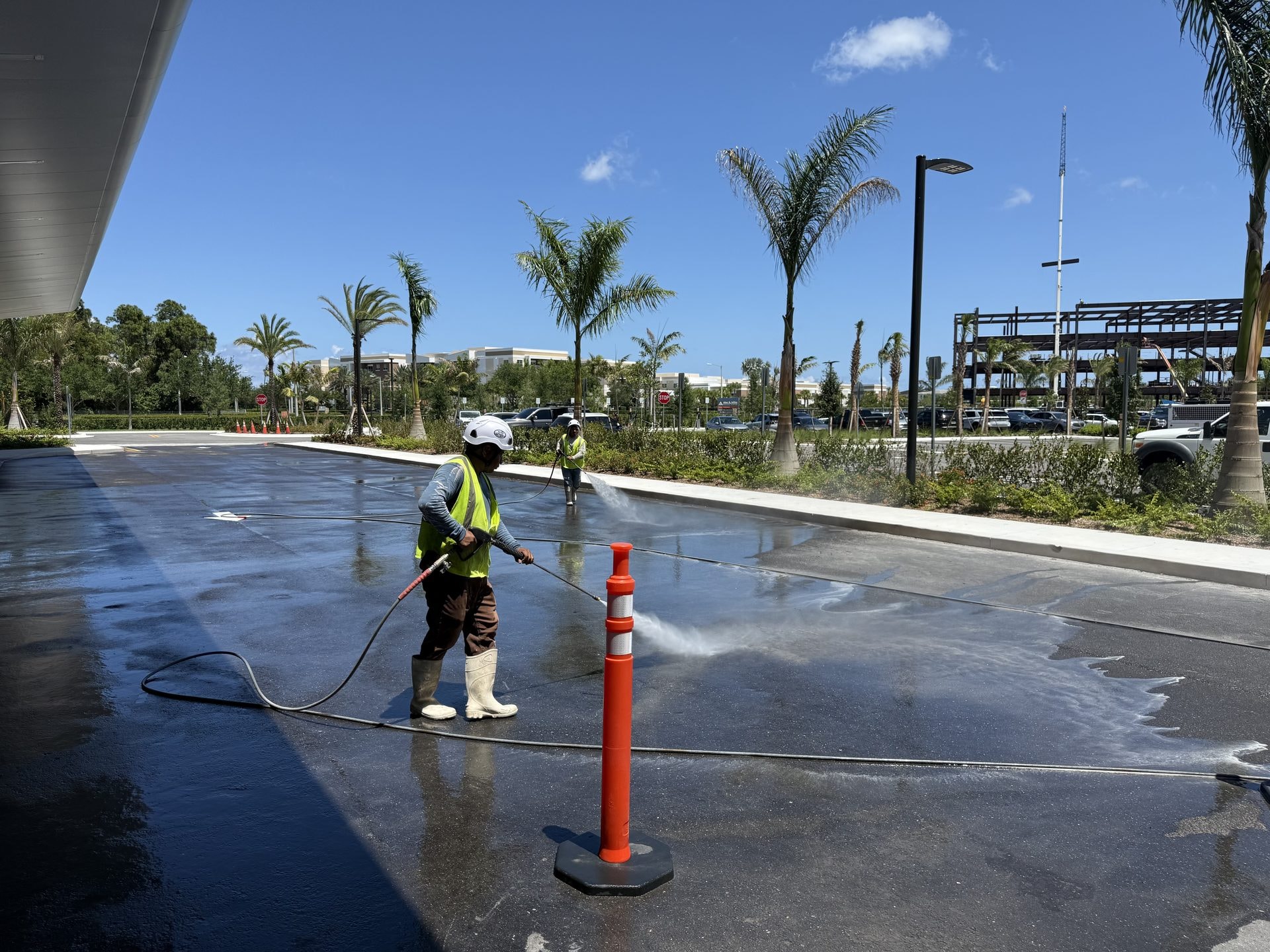 Crew in high visibility vests and hard hats pressure washing the main entrance drive at a medical center, Palm Beach Gardens, FL