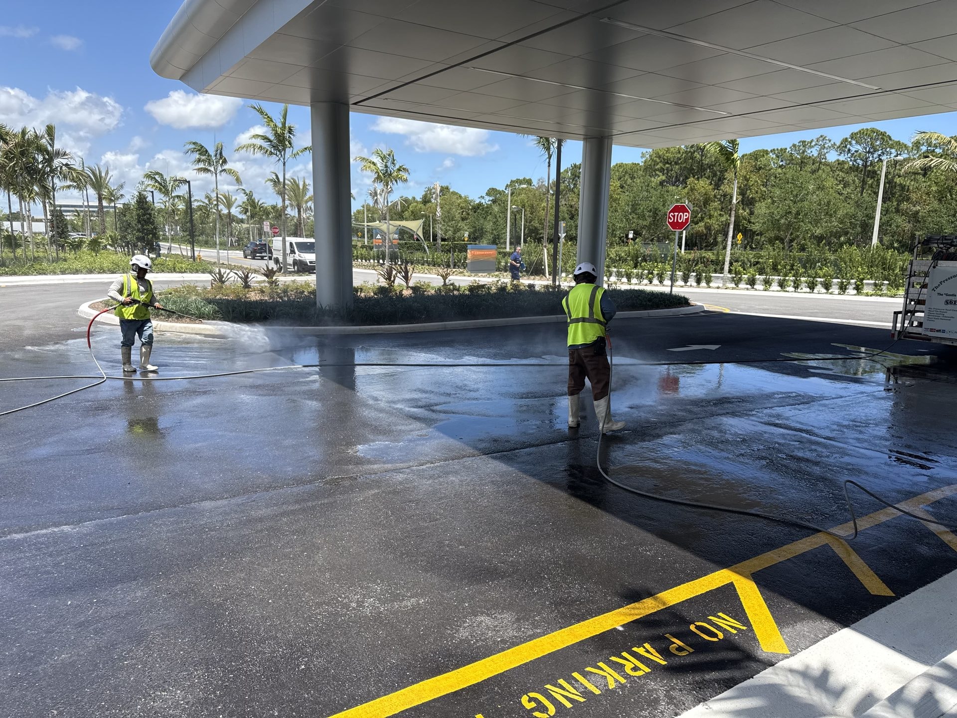 Crew pressure washing the covered emergency entrance drive at a medical center after construction, Palm Beach Gardens, FL