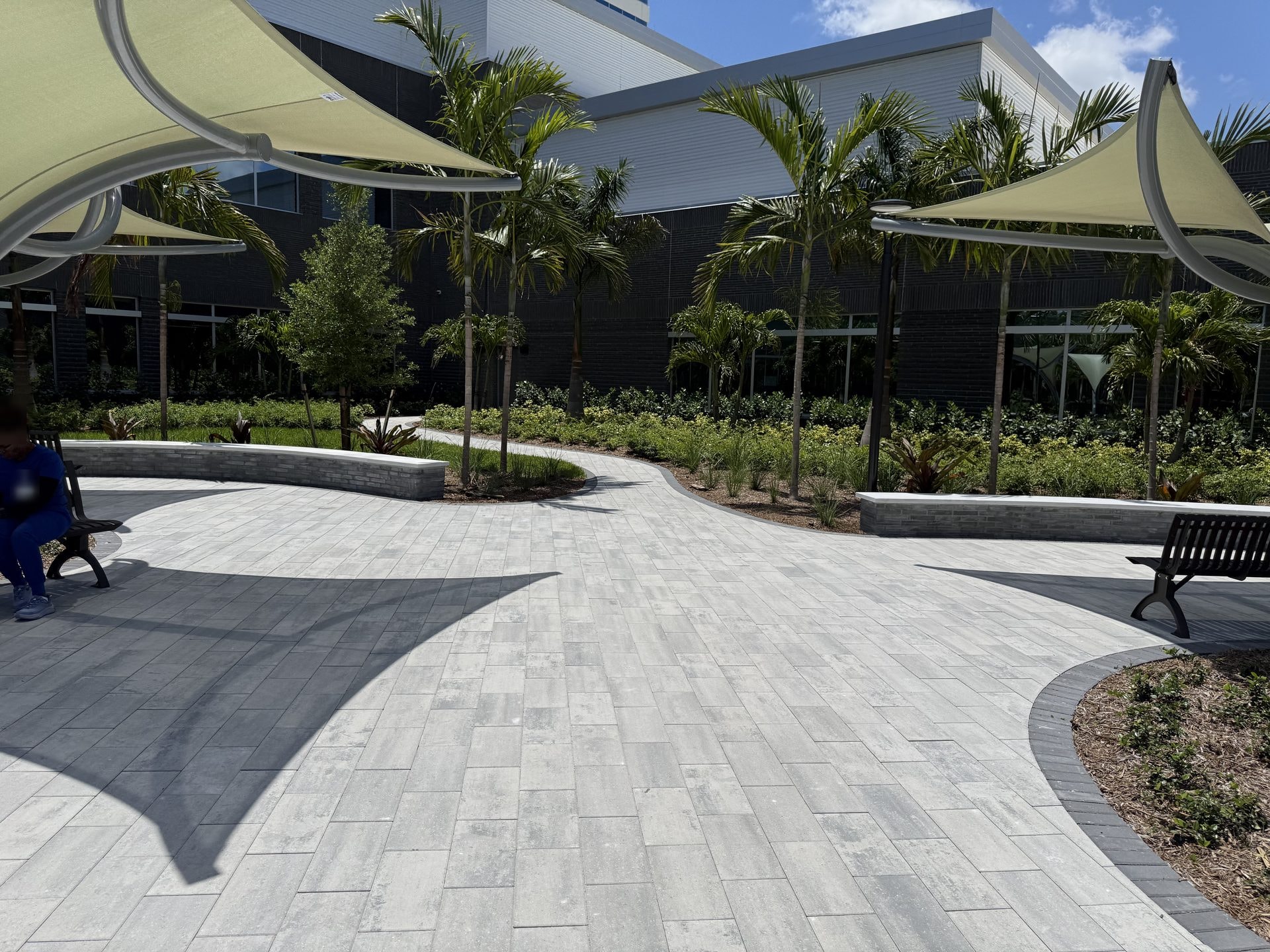 Completed paver plaza with shade sails and benches at a medical center after post-construction cleaning, Palm Beach Gardens, FL