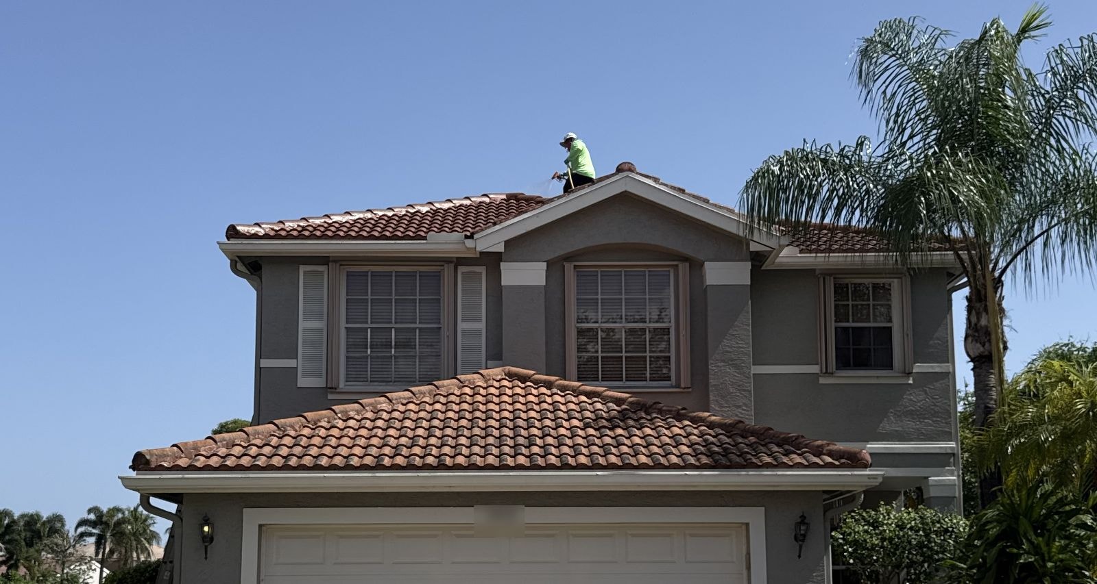Before: Technician applying soft wash solution to a barrel tile roof on a two story home, Greenacres, FL