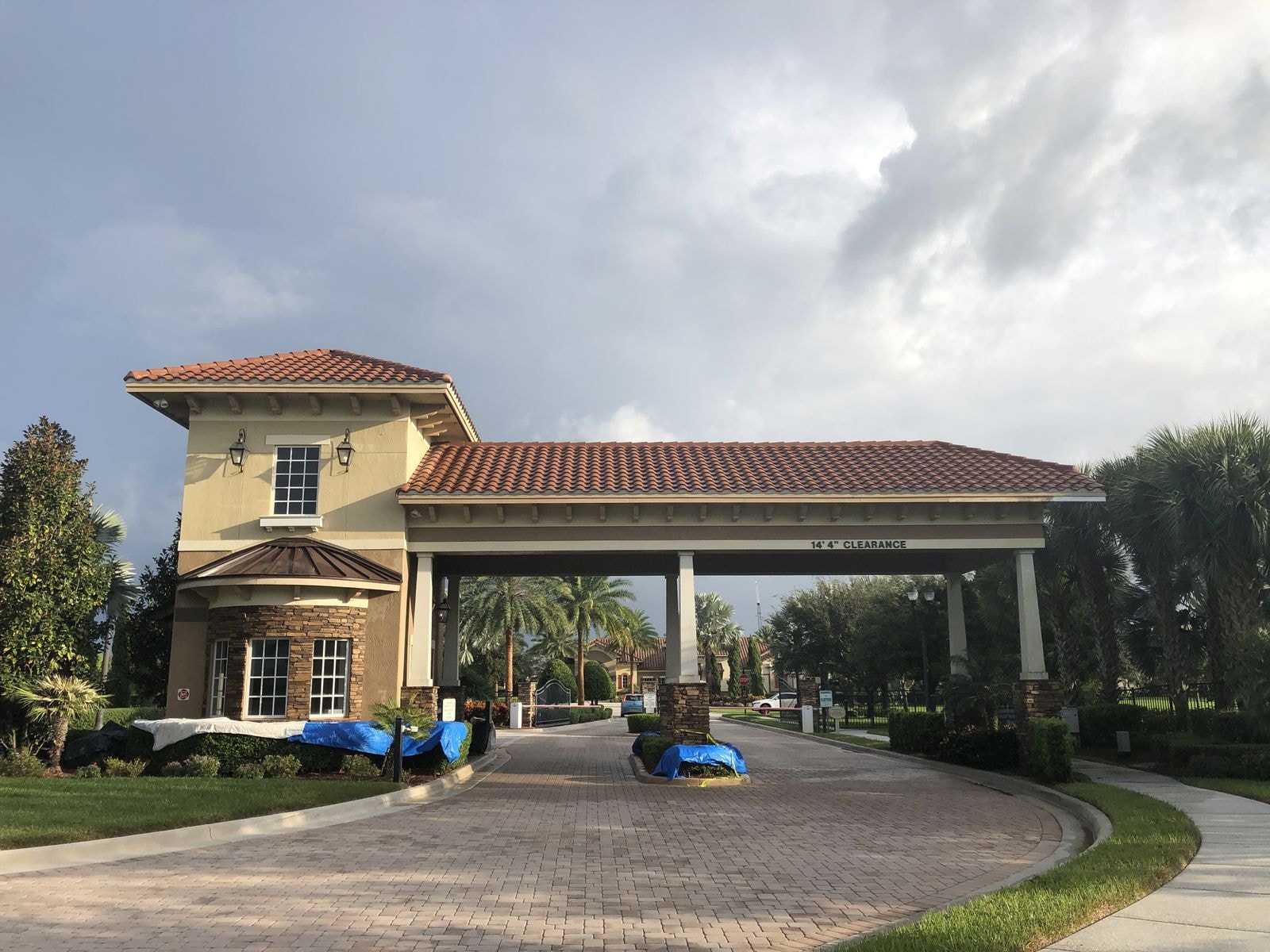 HOA gatehouse barrel tile roof after soft-wash cleaning with the landscaping tarped and protected, Wellington, FL