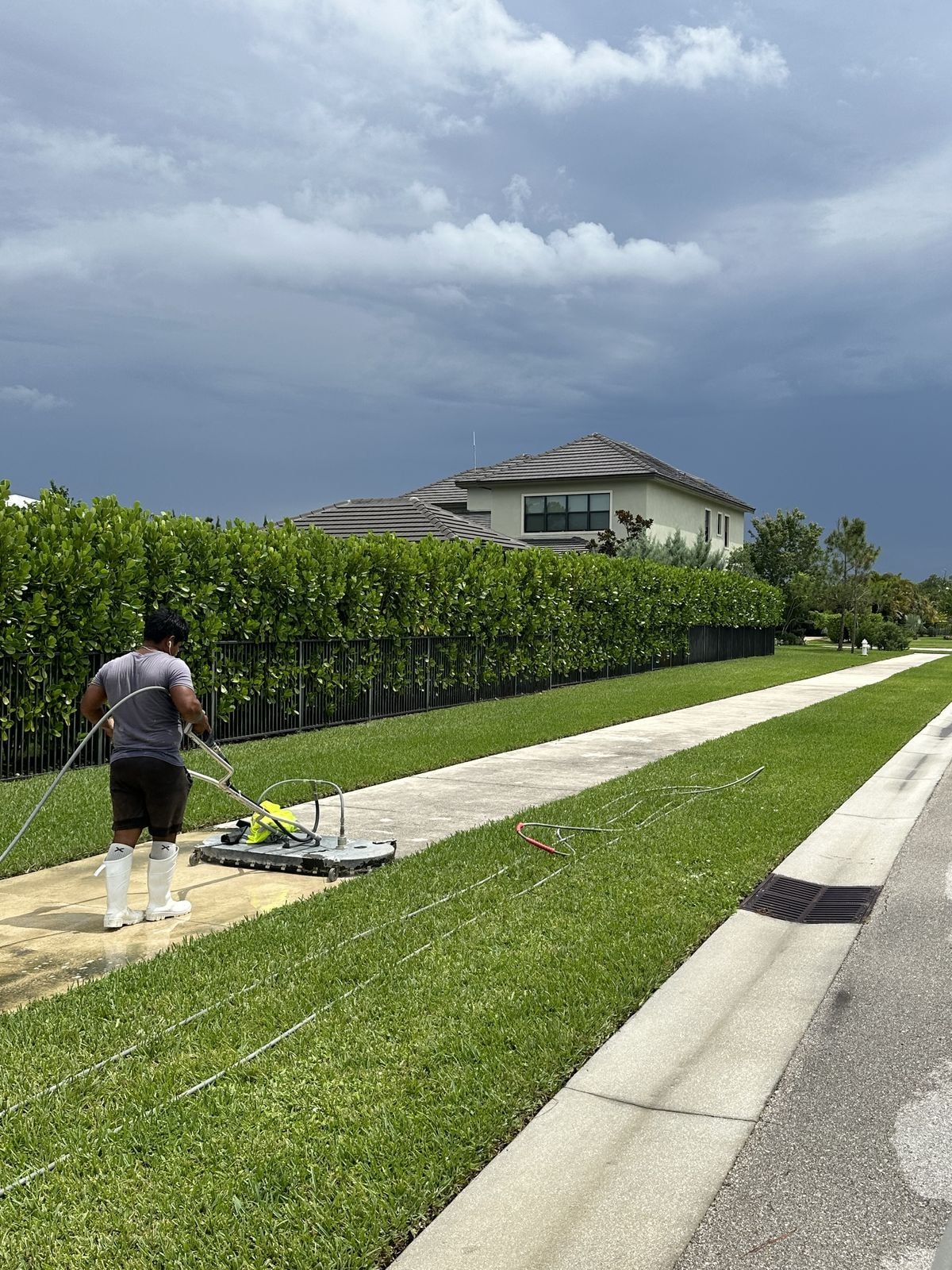 Technician using a surface cleaner on a residential community sidewalk, Jupiter, FL