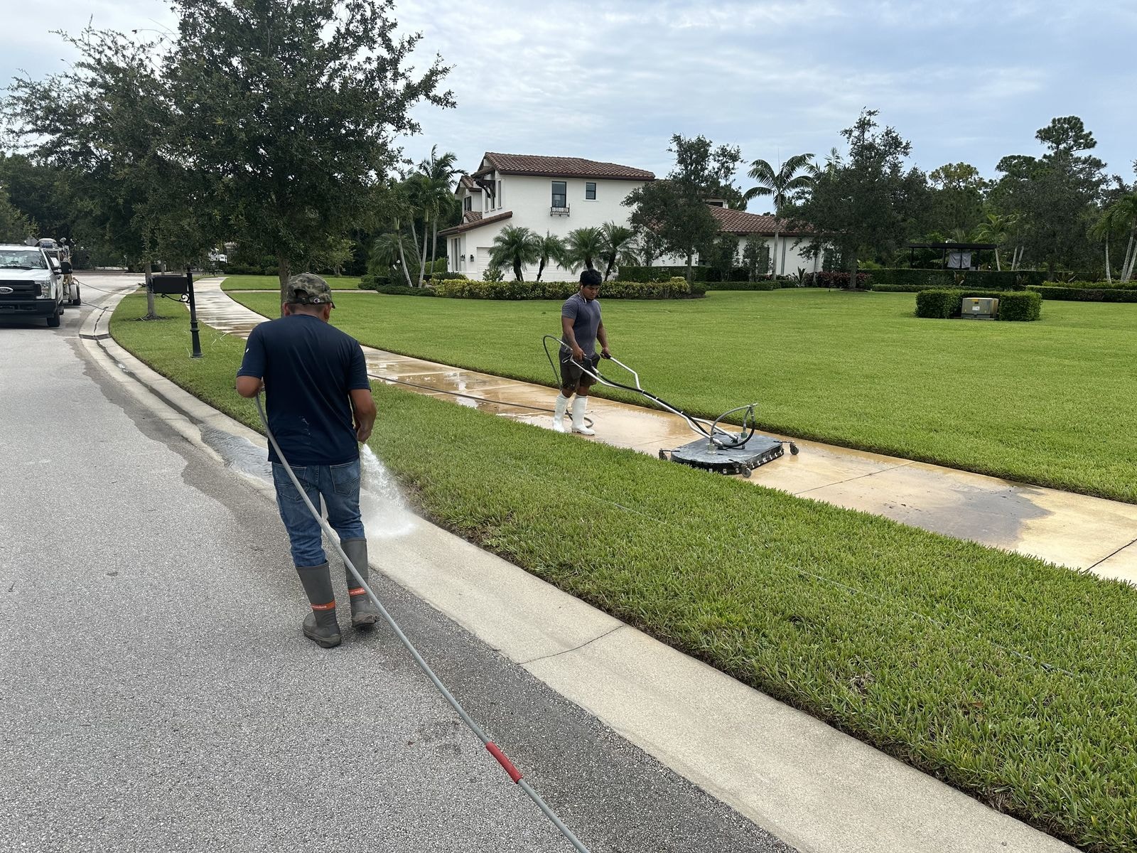 Two-man crew pressure washing a community sidewalk and swale, Jupiter, FL