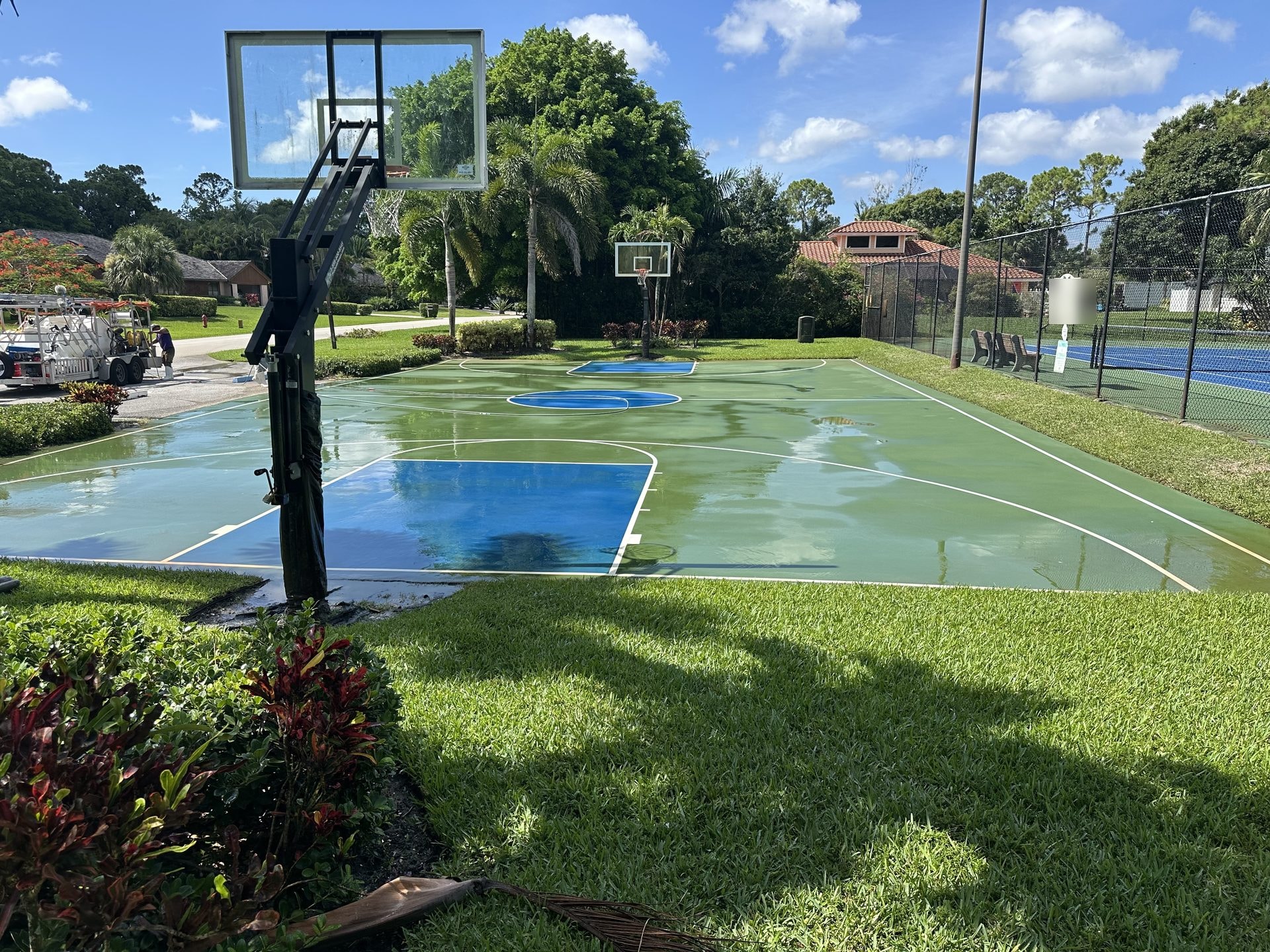 Freshly cleaned community basketball court with painted key and three-point lines, rig on site, Lake Worth, FL