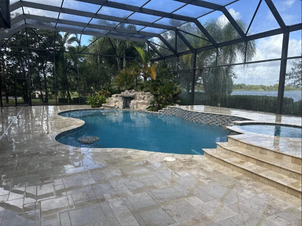 Travertine pool deck inside screened lanai at a Wellington, FL lakefront estate — freshly pressure washed