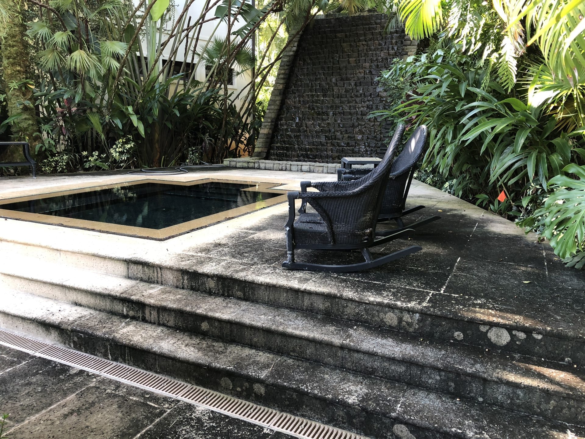 Travertine jacuzzi deck with heavy organic staining before cleaning, Wellington, FL