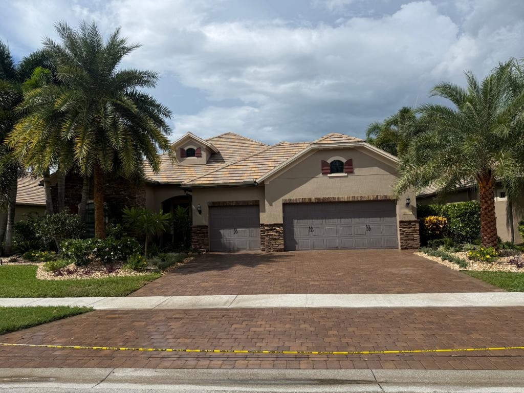 Finished flat tile roof after soft-wash cleaning, with freshly sealed paver driveway at a Wellington, FL home